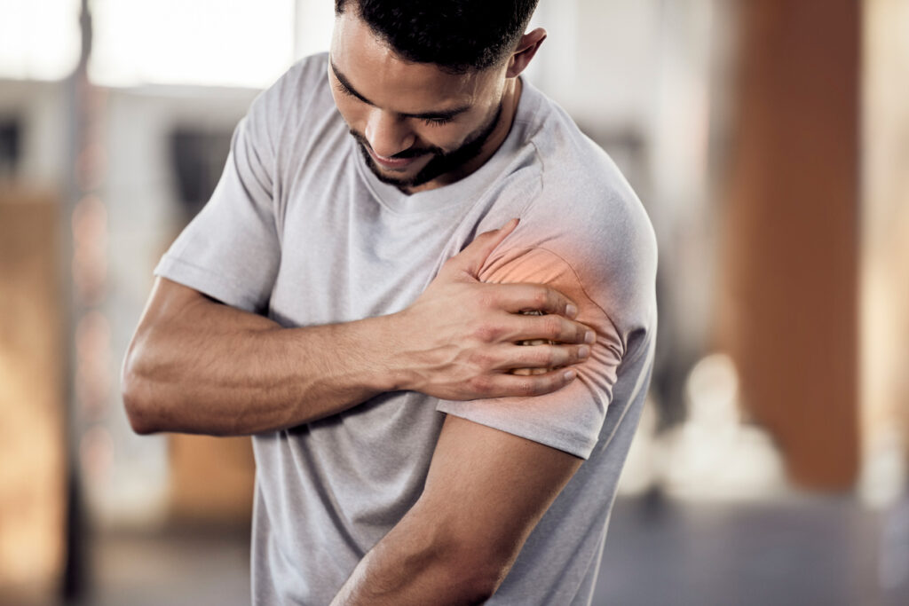 Shot of a muscular young man holding his arm in pain while exercising in a gym