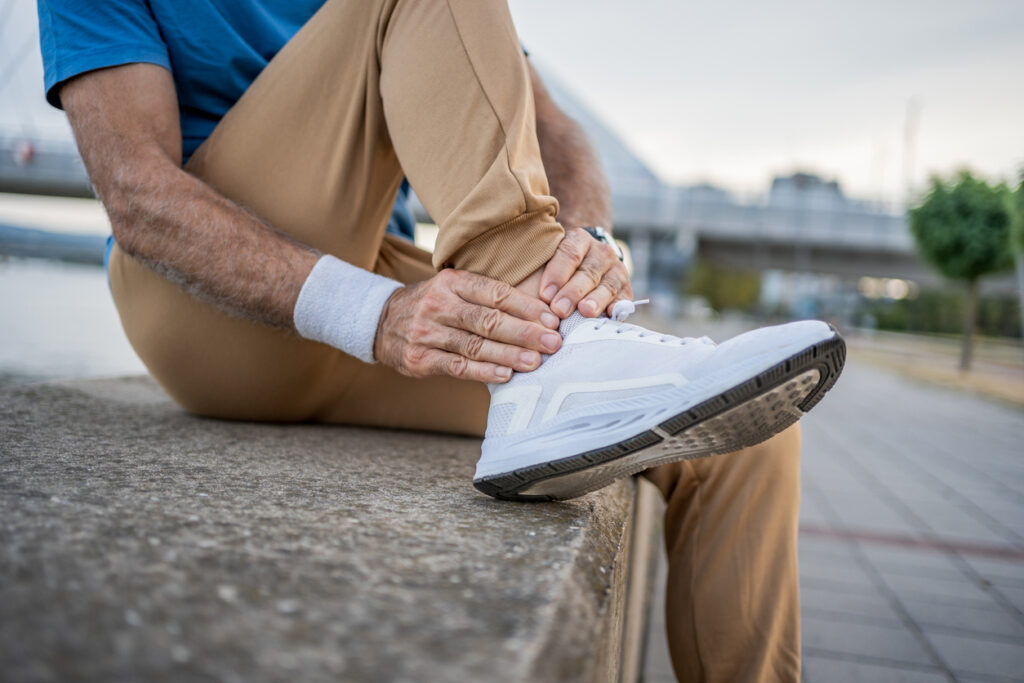 Male runner touching ankle in pain