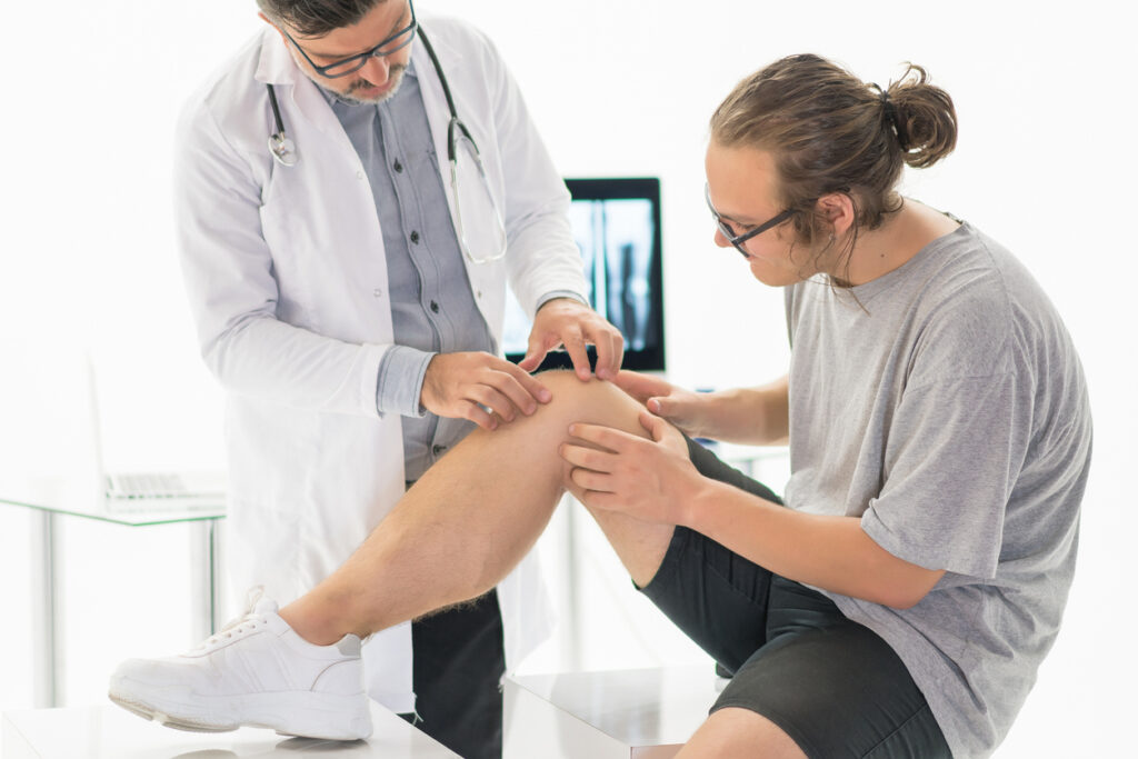 Full length of a young man getting his knee examined