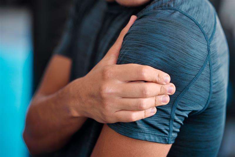 Person holding a painful shoulder